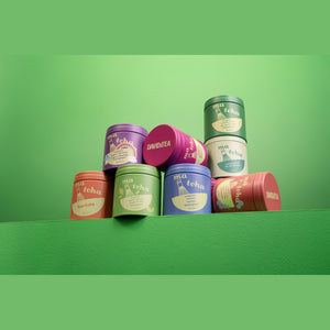 Assorted DAVIDsTEA matcha tea tins stacked together on a green background